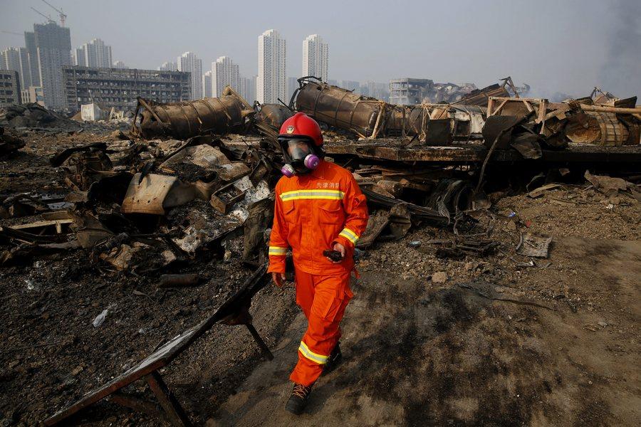 epaselect epa04884508 A fireman wearing a gas mask searches the area of a huge explosion that rocked the port city of Tianjin, China, 15 August 2015. Explosions and a fireball at a chemical warehouse killed at least 85 people in the north-eastern Chinese port city of Tianjin late on 12 August. New explosions rocked a chemical warehouse in northern China as police ordered residents to evacuate buildings within a three-kilometre radius, state media said on 15 August. EPA/WU HONG